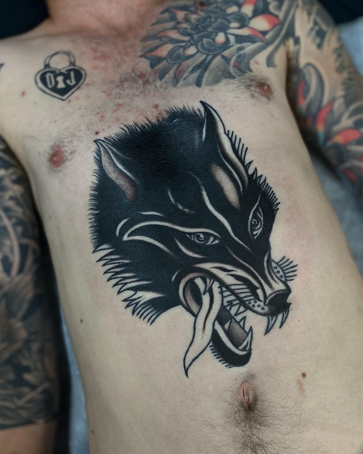 Solid black wolf head with bared teeth tattooed across the centre of