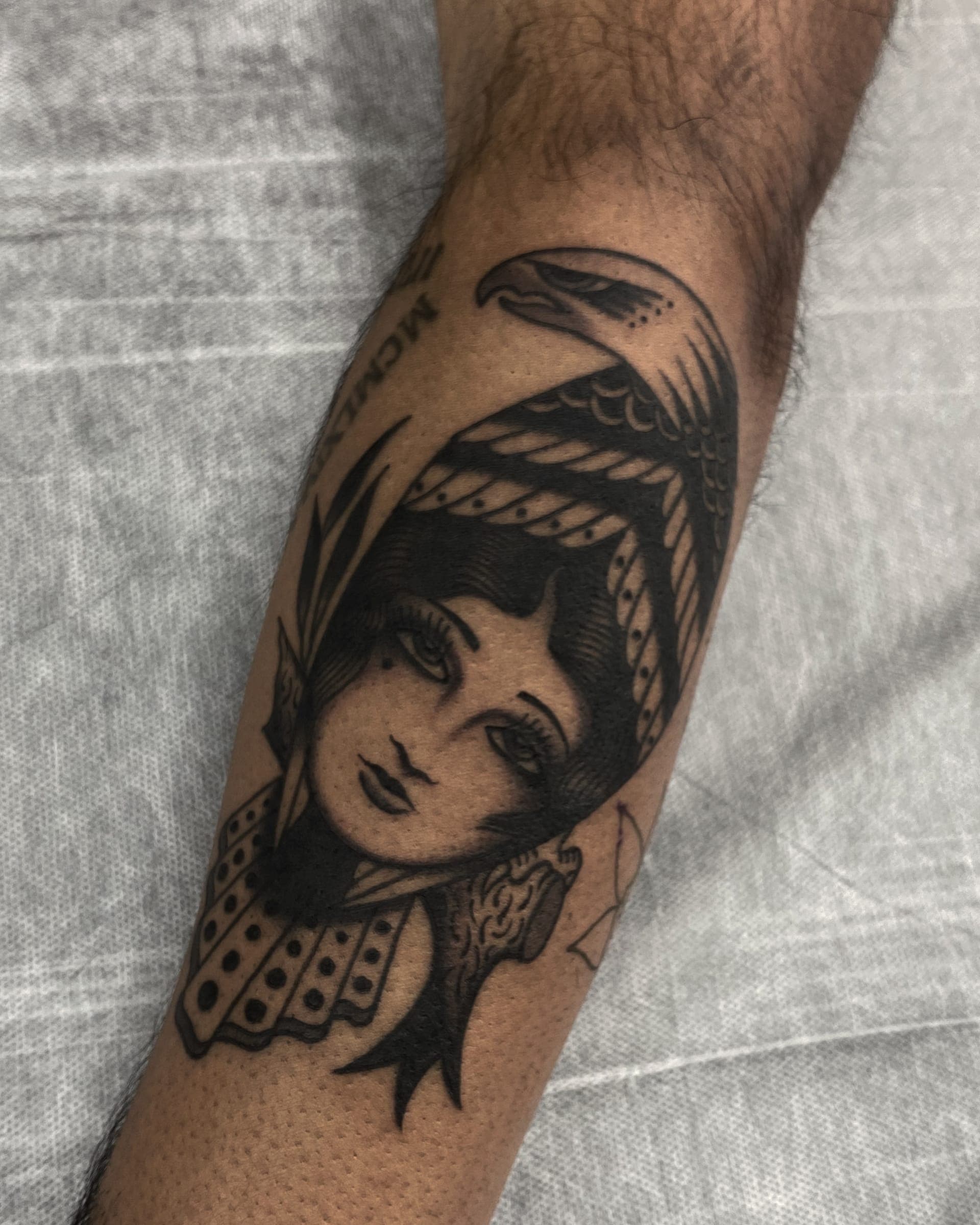 Black and grey traditional eagle perched above a girl head