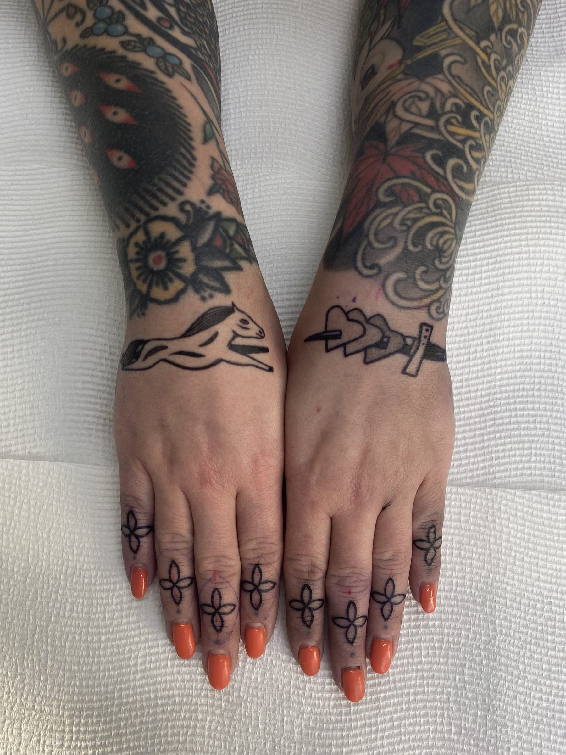 Fine-line horse, dagger and small four-petal tattoos